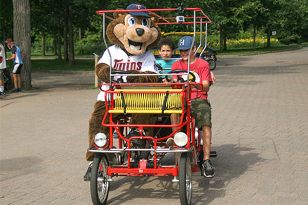 Kids riding in a surry bike with T.C. Bear